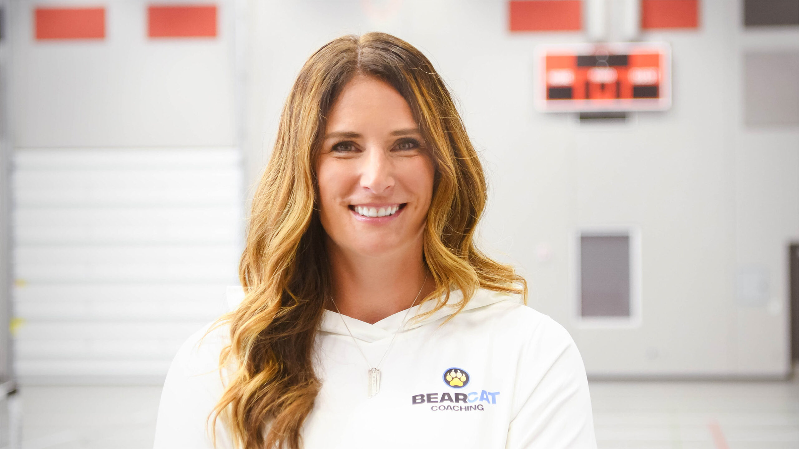 Cathy Helin in a white polo indoors, confident representing mindset coaching for athletes, parents, and coaches.