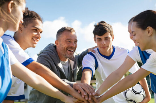 Sport coach motivating young athletes during team huddle, building leadership, communication, confidence, teamwork, and winning mindset together.