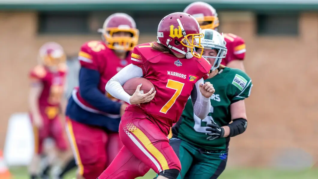 A football player in a red uniform runs with the ball during an intense competitive game.