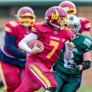 A football player in a red uniform runs with the ball during an intense competitive game.
