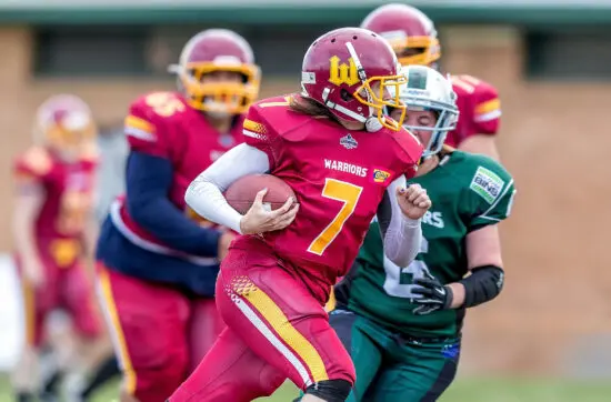A football player in a red uniform runs with the ball during an intense competitive game.